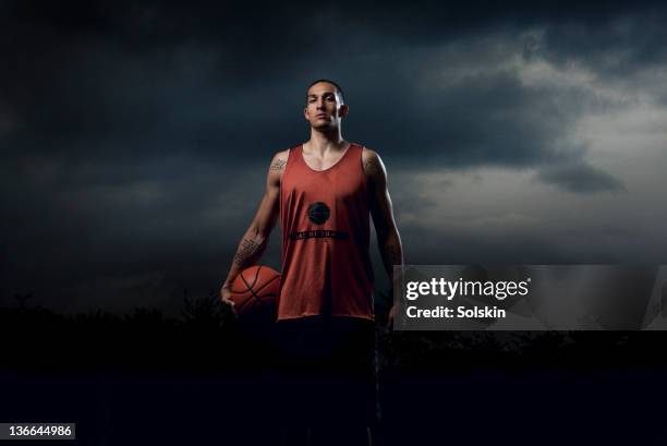 basketball player holding ball - moody sky foto e immagini stock