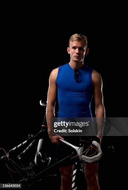 athlete man holding cycle over shoulder - indoor triathlon stock pictures, royalty-free photos & images