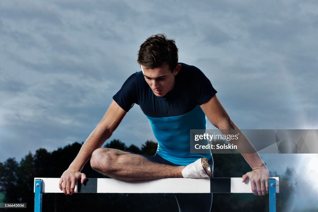 Track and field athlete warming up on hurdle