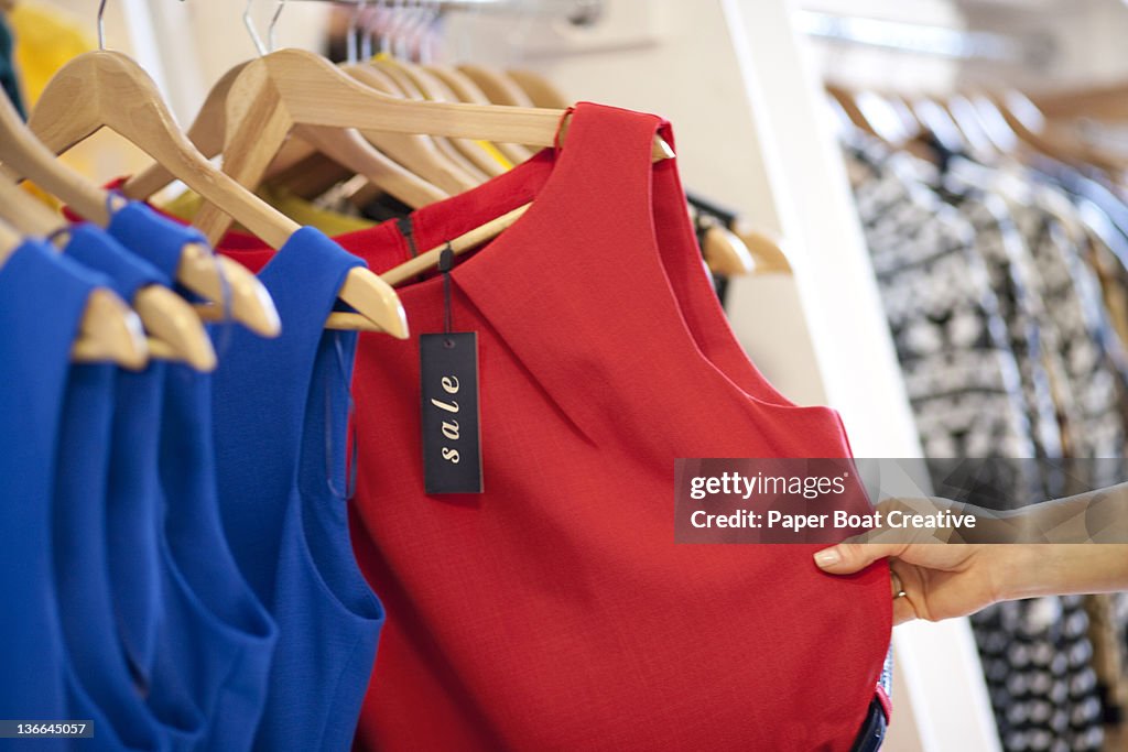 Close up of a woman selecting a red dress on sale