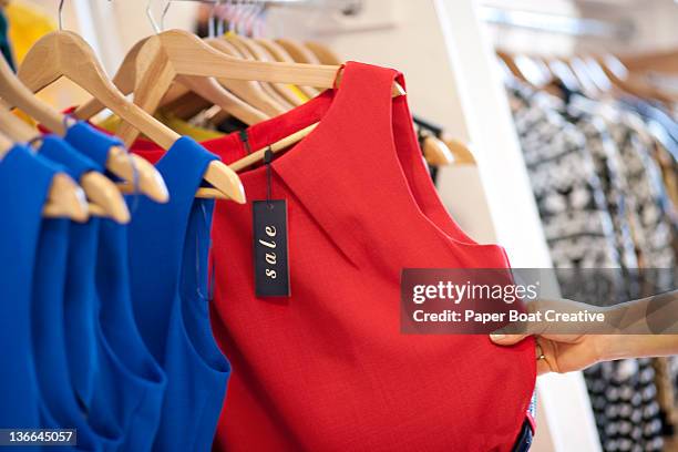 close up of a woman selecting a red dress on sale - clothing racks stock pictures, royalty-free photos & images