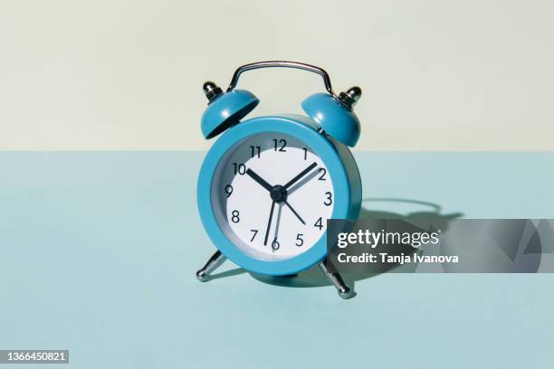 alarm clock on a blue and beige background - routine fotografías e imágenes de stock