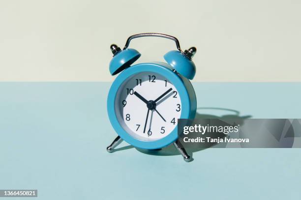 alarm clock on a blue and beige background - urgency abstract stock pictures, royalty-free photos & images