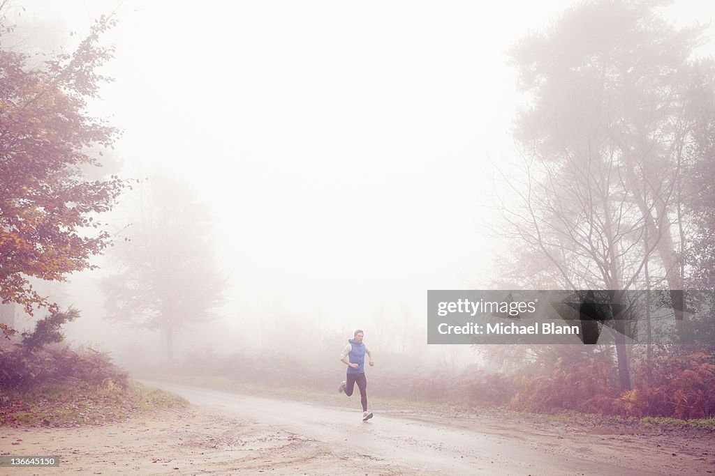 Man running along countryside road in fog