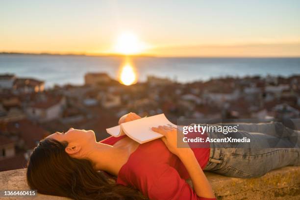 young woman relaxes above mediterranean village, at sunrise - book top view stockfoto's en -beelden