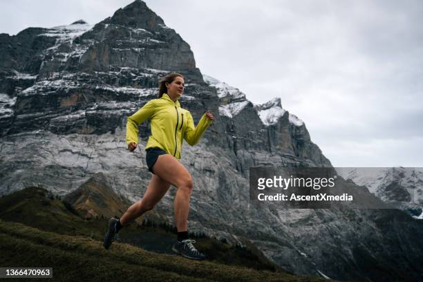 athletic woman runs through the swiss alps in early autumn - coat drive stock pictures, royalty-free photos & images