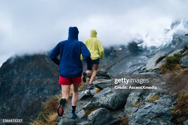 two women run through the swiss alps in early autumn - conversion sport stock pictures, royalty-free photos & images