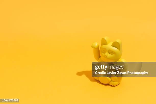 lucky cat (maneki neko) against yellow background - maneki neko 個照片及圖片檔