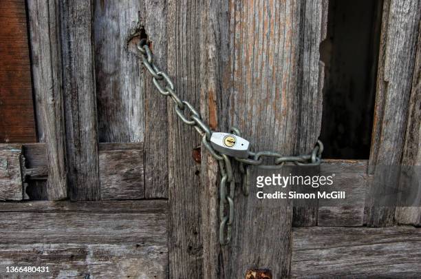 chained and padlocked old rotting wooden double doors of an abandoned building - wood rot stock pictures, royalty-free photos & images
