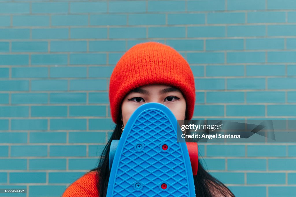 Cool Asian Woman Hiding Her Face With A Skateboard