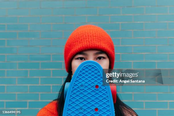 cool asian woman hiding her face with a skateboard - womens free skate imagens e fotografias de stock