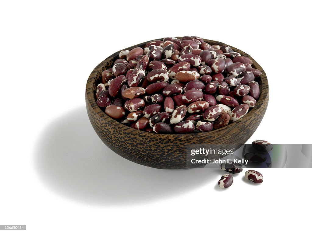 Dried Anasazi beans in wood bowl on white