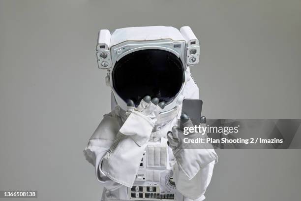 an astronaut with a smartphone - space helmet stock-fotos und bilder