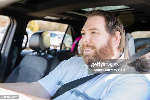 family with two young daughters driving in suv while children sit in car seats and watch dvd together - dvd speler stockfoto's en -beelden