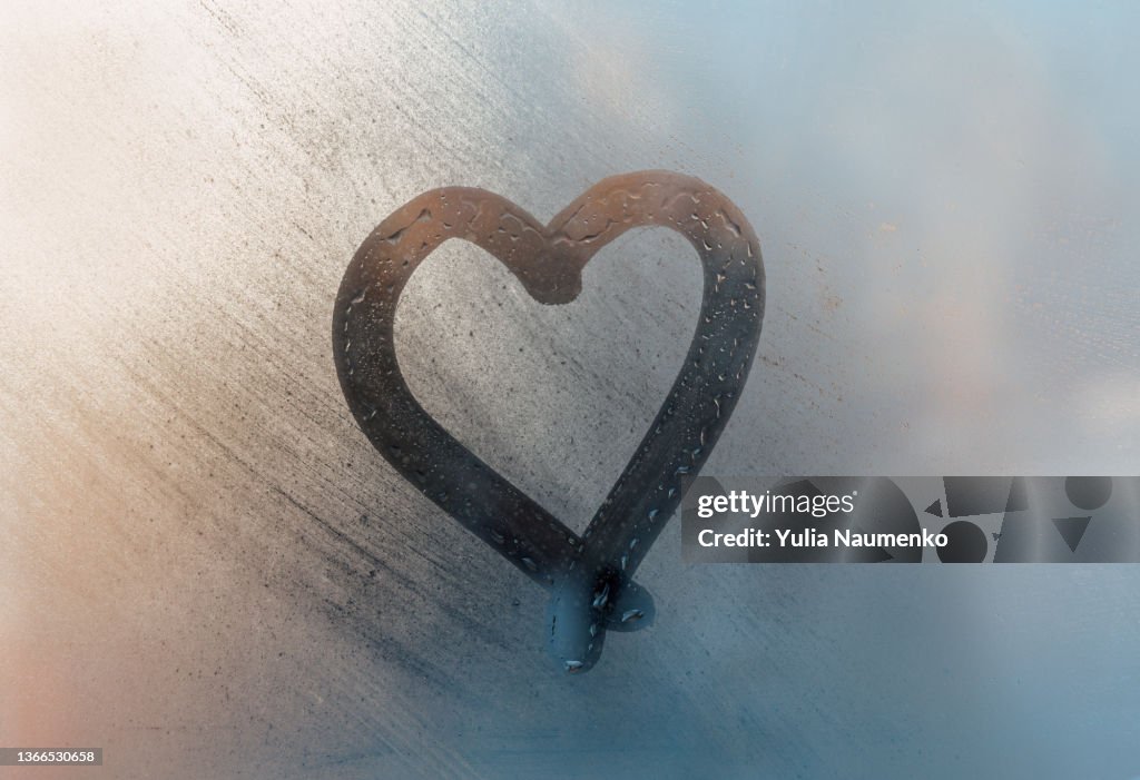 A heart was painted on a misted window. Drawn with a finger on wet glass.