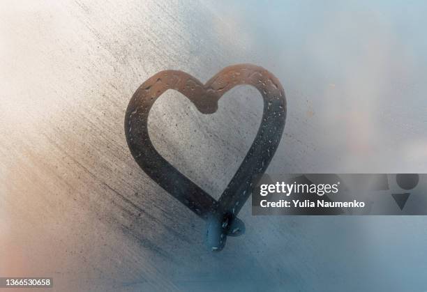 a heart was painted on a misted window. drawn with a finger on wet glass. - verre dépoli photos et images de collection