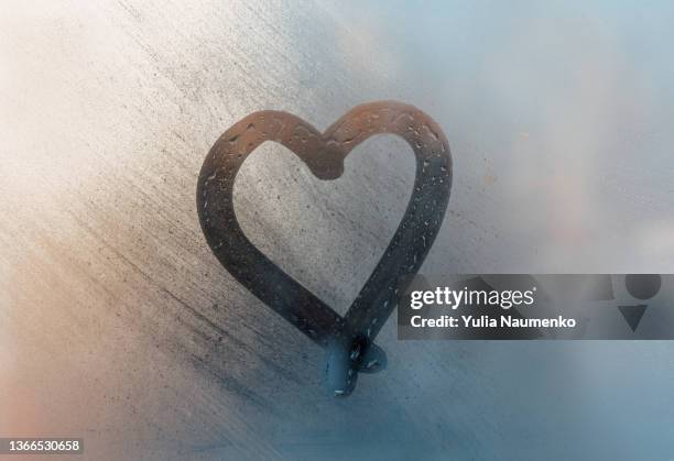 a heart was painted on a misted window. drawn with a finger on wet glass. - condensation stock pictures, royalty-free photos & images
