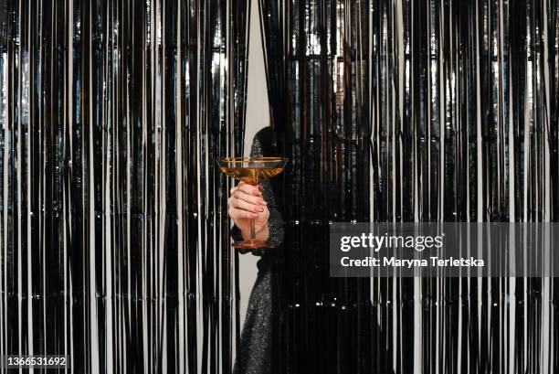 the girl holds a glass of champagne in her hands. silver dress. silvery background. silver tinsel. glass in hand. - veleiding stockfoto's en -beelden