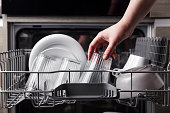 Open dishwasher with clean cutlery, glasses, dishes inside in the home kitchen