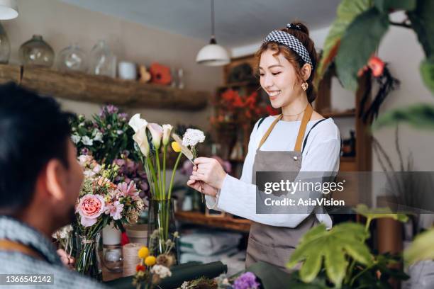 若いアジアの女性花屋、中小企業の花屋のオーナー、花のジャミングワークショップをやって、学生に花の花束の配置に関するチュートリアルを与えます。中小企業、アート、クラフトワー� - flower art ストックフォトと画像