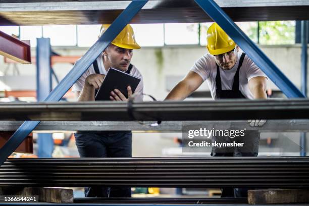 dois trabalhadores metais cooperando enquanto estiver trabalhando com ferro em fábrica de alumínio. - indústria metalúrgica - fotografias e filmes do acervo