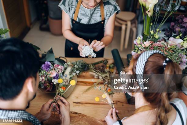 cropped shot of young asian couple attending a floral jamming workshop, making a flower bouquet assisting by an experienced florist. small business, art and craft workshop, hobbies concept - friends studio shot stock pictures, royalty-free photos & images