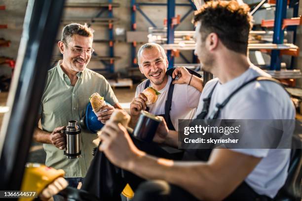 happy manual workers and their manager talking on lunch break in a factory. - lunch stockfoto's en -beelden