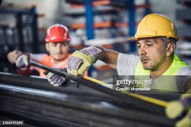 metal workers cooperating while measuring steel in aluminum mill. - steel worker stock pictures, royalty-free photos & images