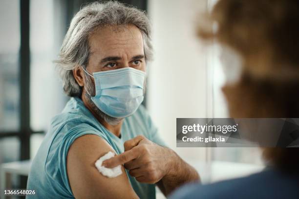 mid adult man receiving covid-19 vaccine. - receiving treatment concerned stock pictures, royalty-free photos & images