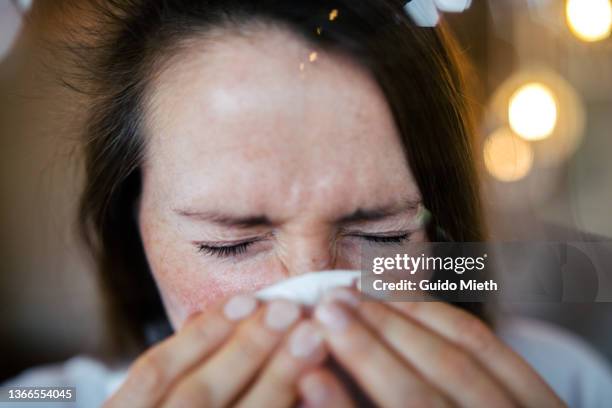 woman rubbing nose while having a flue at home. - allergie foto e immagini stock