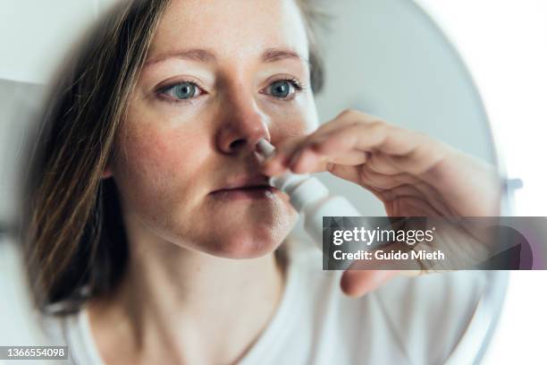 woman cleaning her nose with salt solution nasal spray, beeing ill. - nasenspray stock-fotos und bilder