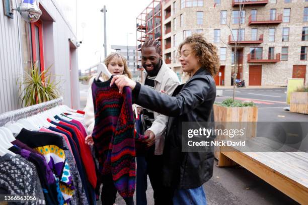 friends shopping at a vintage clothes market - spending money stockfoto's en -beelden