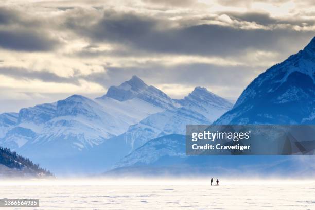 people walking on frozen lake. alberta, banff national park, lake louise . frozen lake, tourist walking on ice. - winter wilderness stock pictures, royalty-free photos & images