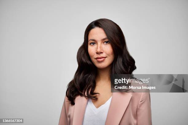 happy mixed race female brunette ceo wearing pink blazer. - portrait stock-fotos und bilder