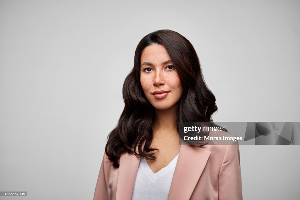 Happy Mixed Race Female Brunette CEO Wearing Pink Blazer.