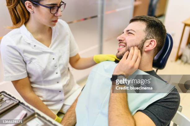 mann mit zahnschmerzen beim zahnarzt - sensitivity in tooth stock-fotos und bilder