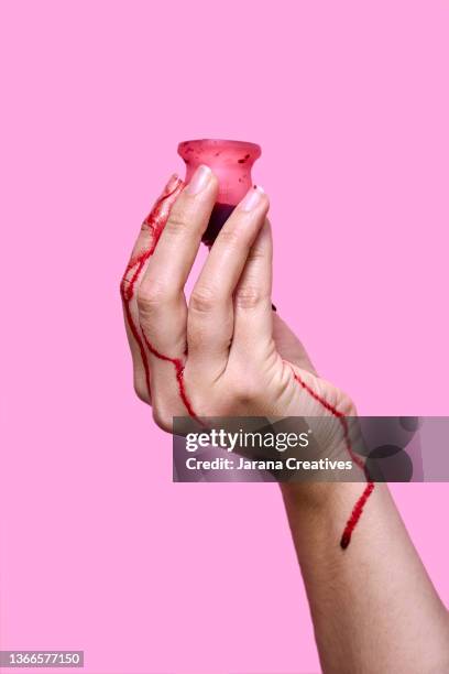 a woman's hand with a menstrual cup - period blood stockfoto's en -beelden