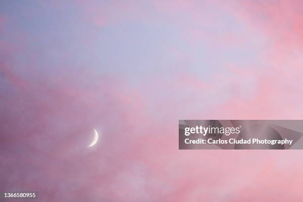 crescent moon between clouds at sunset - crescent stock pictures, royalty-free photos & images