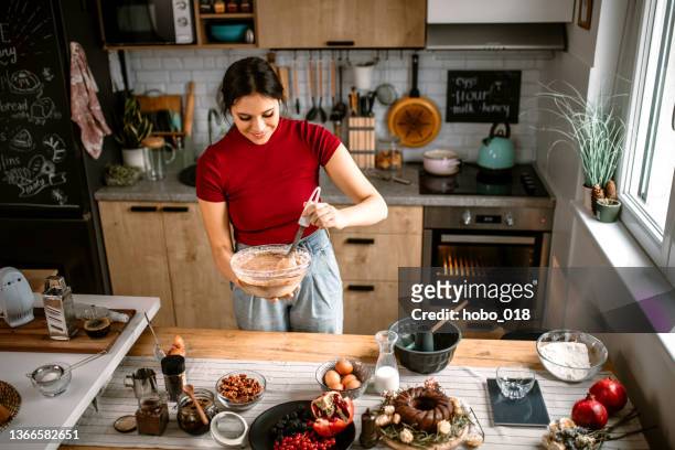 woman mixing cake batter with silicone spatula - making cake stockfoto's en -beelden