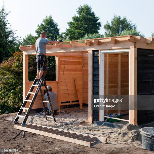 two men building a domestic wooden garden shed - man shed stock pictures, royalty-free photos & images