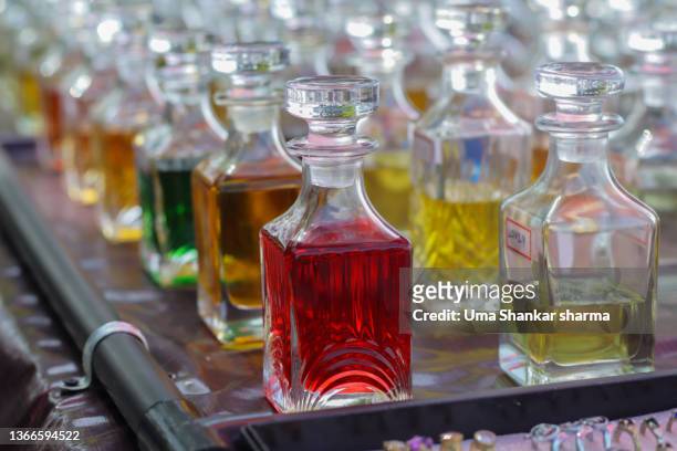 closeup of glass bottles filled with colourfull perfumes scents. - fragrance launch stock-fotos und bilder