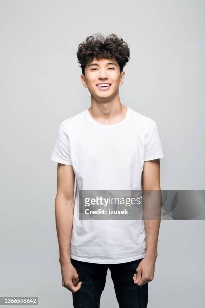 giovane amichevole in t-shirt bianca - man standing against grey background foto e immagini stock