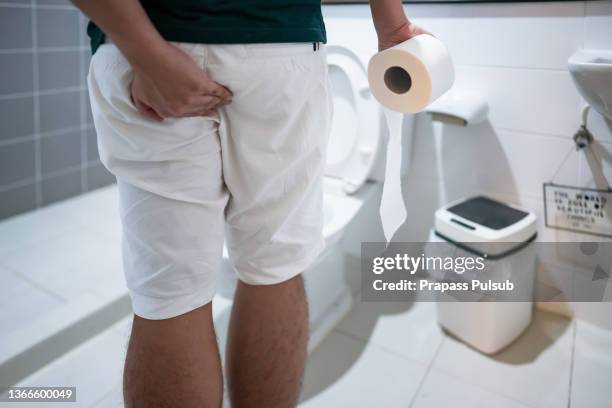 man holding toilet paper roll in bathroom - men taking a dump stock pictures, royalty-free photos & images