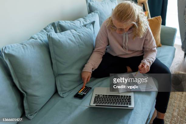 blonde woman paying household bills - manage invest stock pictures, royalty-free photos & images
