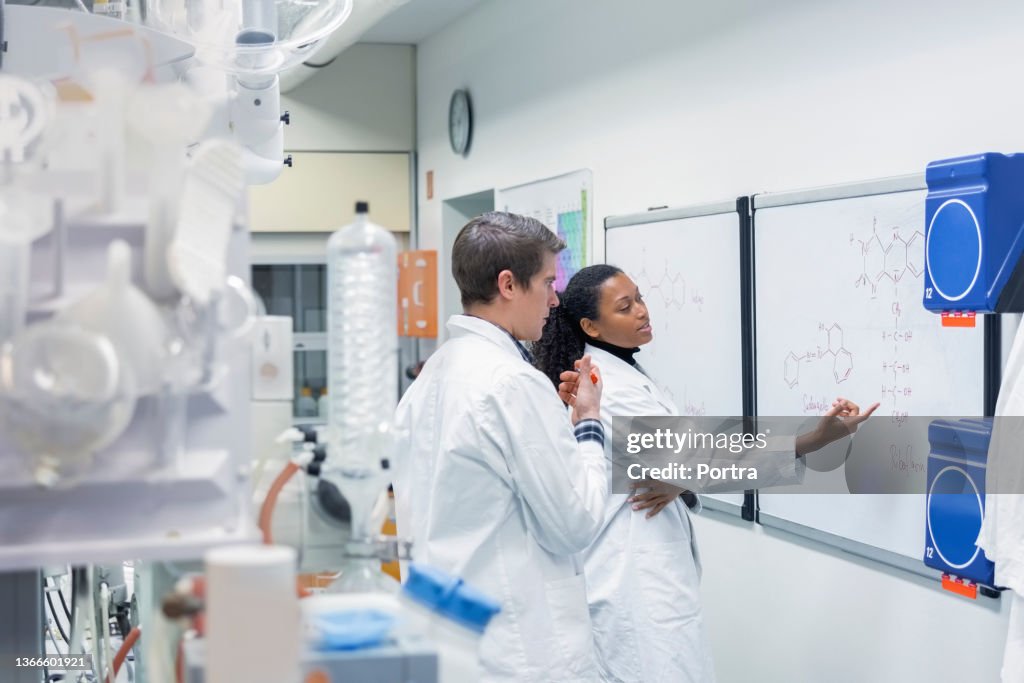 Two researchers discussing about chemistry on a whiteboard