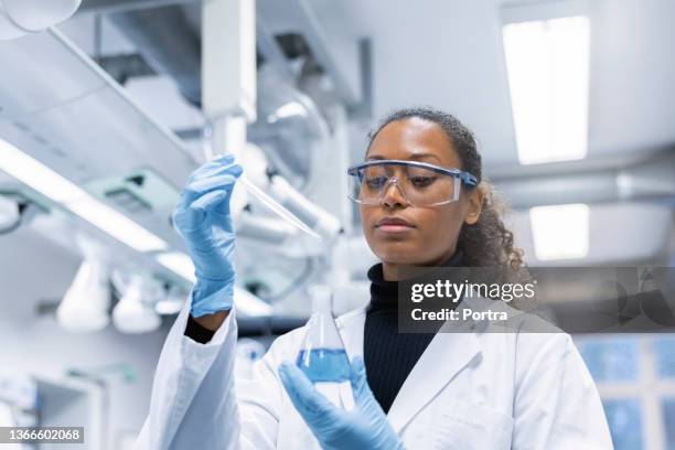 woman scientist experimenting with chemicals in lab - químico imagens e fotografias de stock