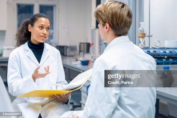 wissenschaftlerin diskutiert neueste erkenntnisse mit laborkollegin - biologist stock-fotos und bilder