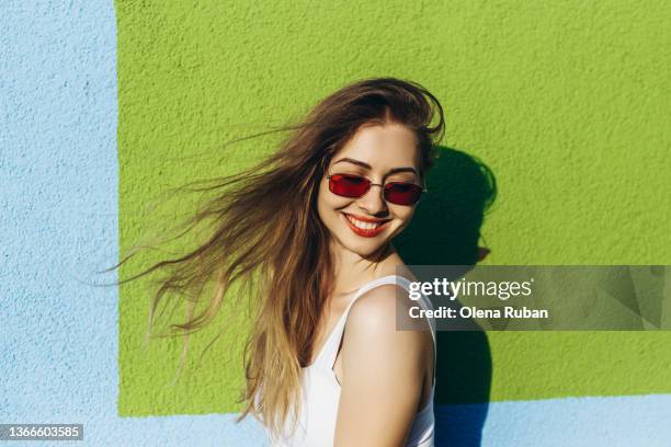 young woman with wind-blown hair. - frau mit sonnenbrille stock-fotos und bilder