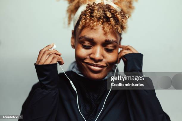 porträt einer afroamerikanischen frau in sportbekleidung, die musik hört - headband stock-fotos und bilder