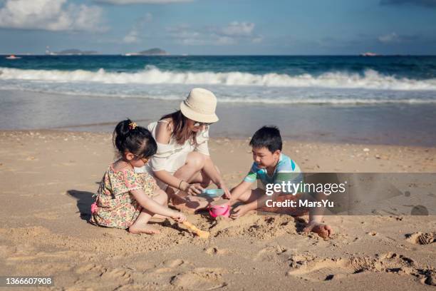 mutter und ihre kinder spielen auf der strand - kind sandburg stock-fotos und bilder